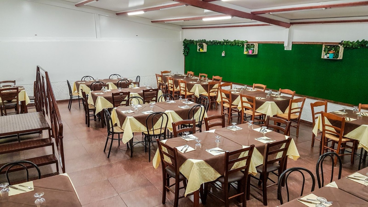 La sala del ristorante, con i tavoli apparecchiati e la parete verde